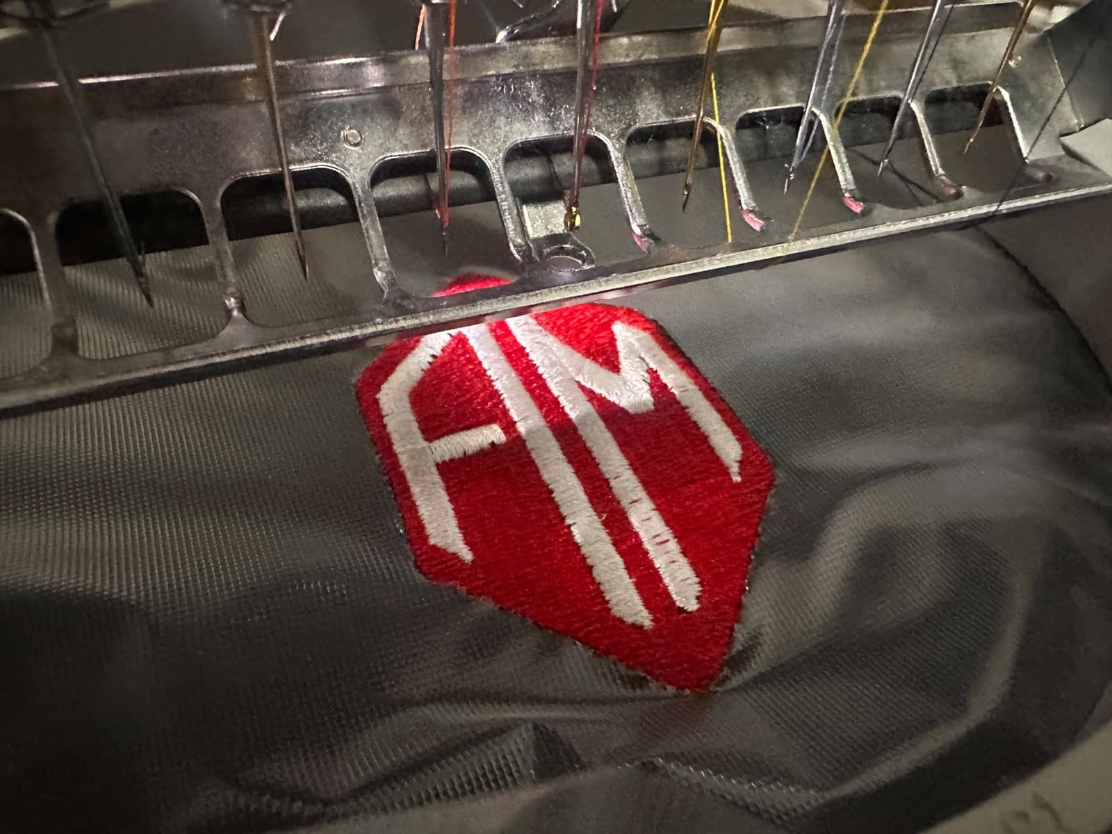 Stickerei auf schwarzem Textil, Logo FM
